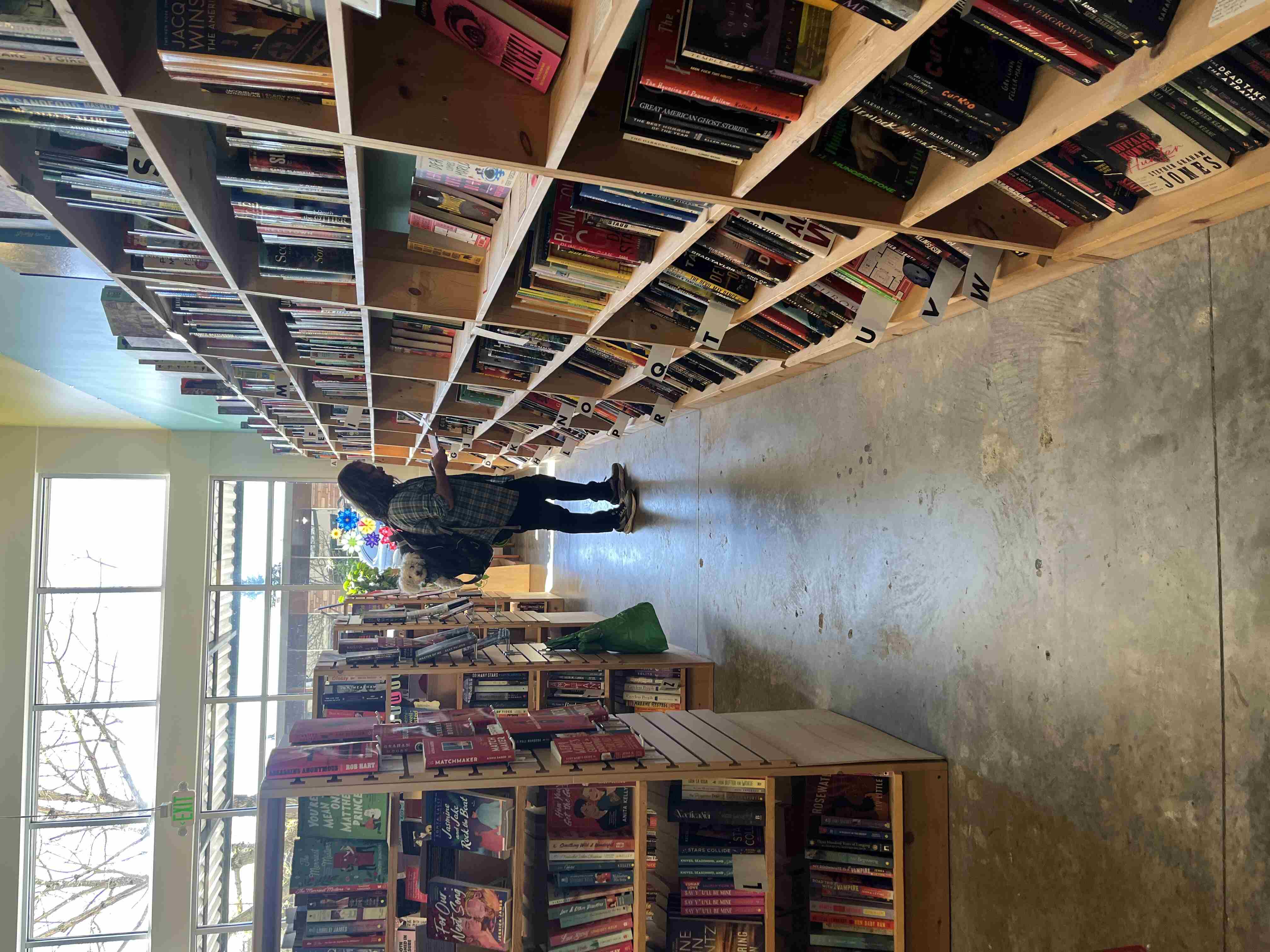 A man carrying a dog in a backpack browses in a bookstore