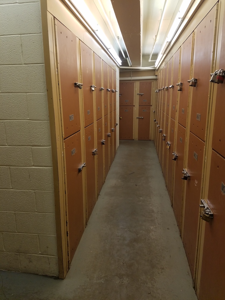 A narrow hallway lined with small tan storage lockers.